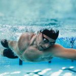 Underwater shot of fit swimmer training in the pool. Professional male swimmer inside swimming pool.